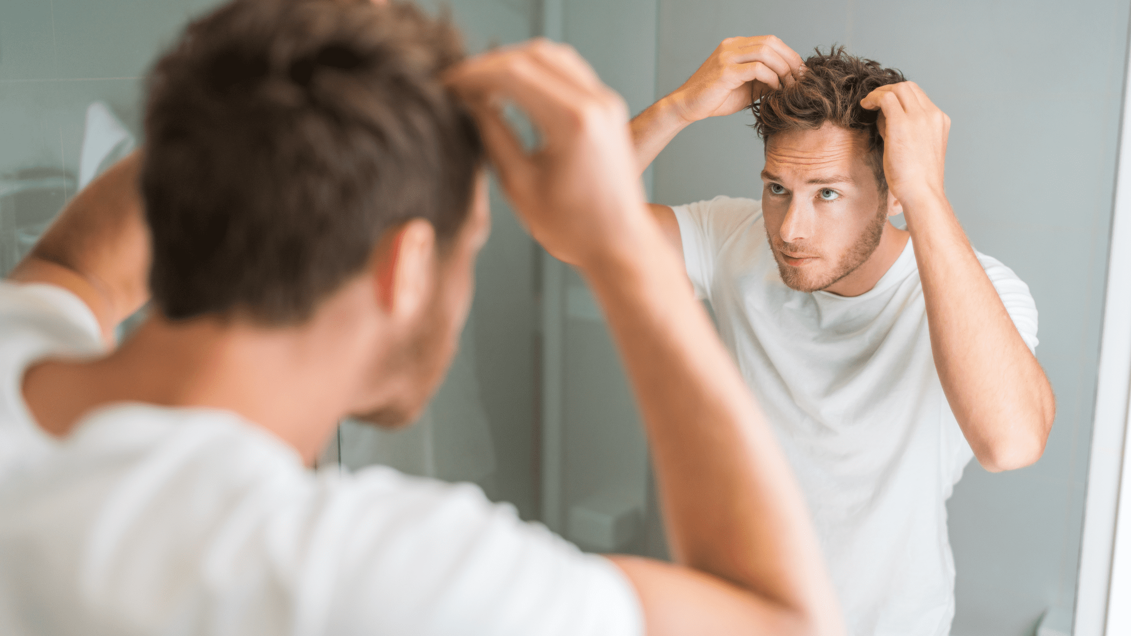 man checking hair in mirror